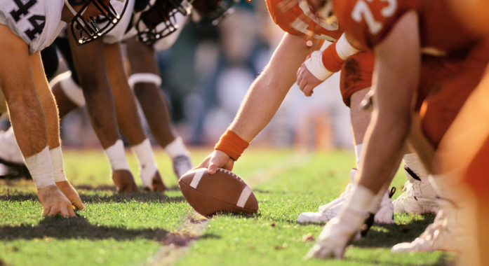 A close-up image of a football game at the line of scrimmage.